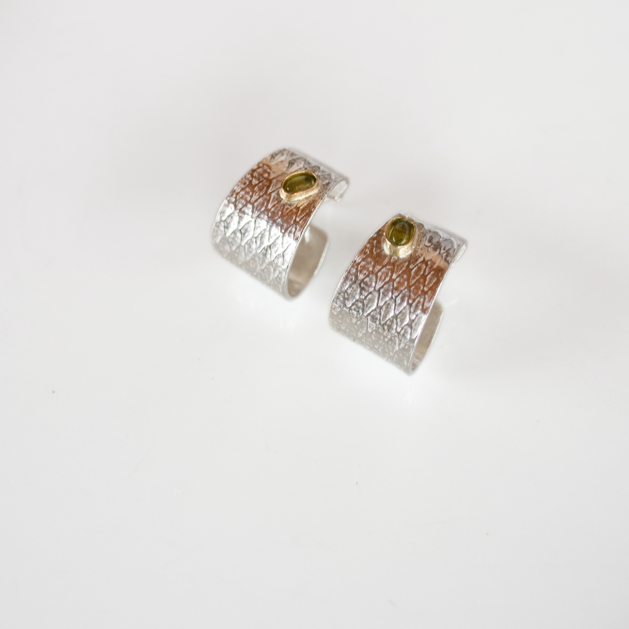 Reptilia silver earring with peridot, side view of the cuff-like shape.