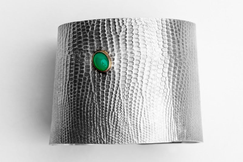 Flat-lay of the Reptilia Maxima silver cuff with green chrysoprase cabochon and snake-scale texture.