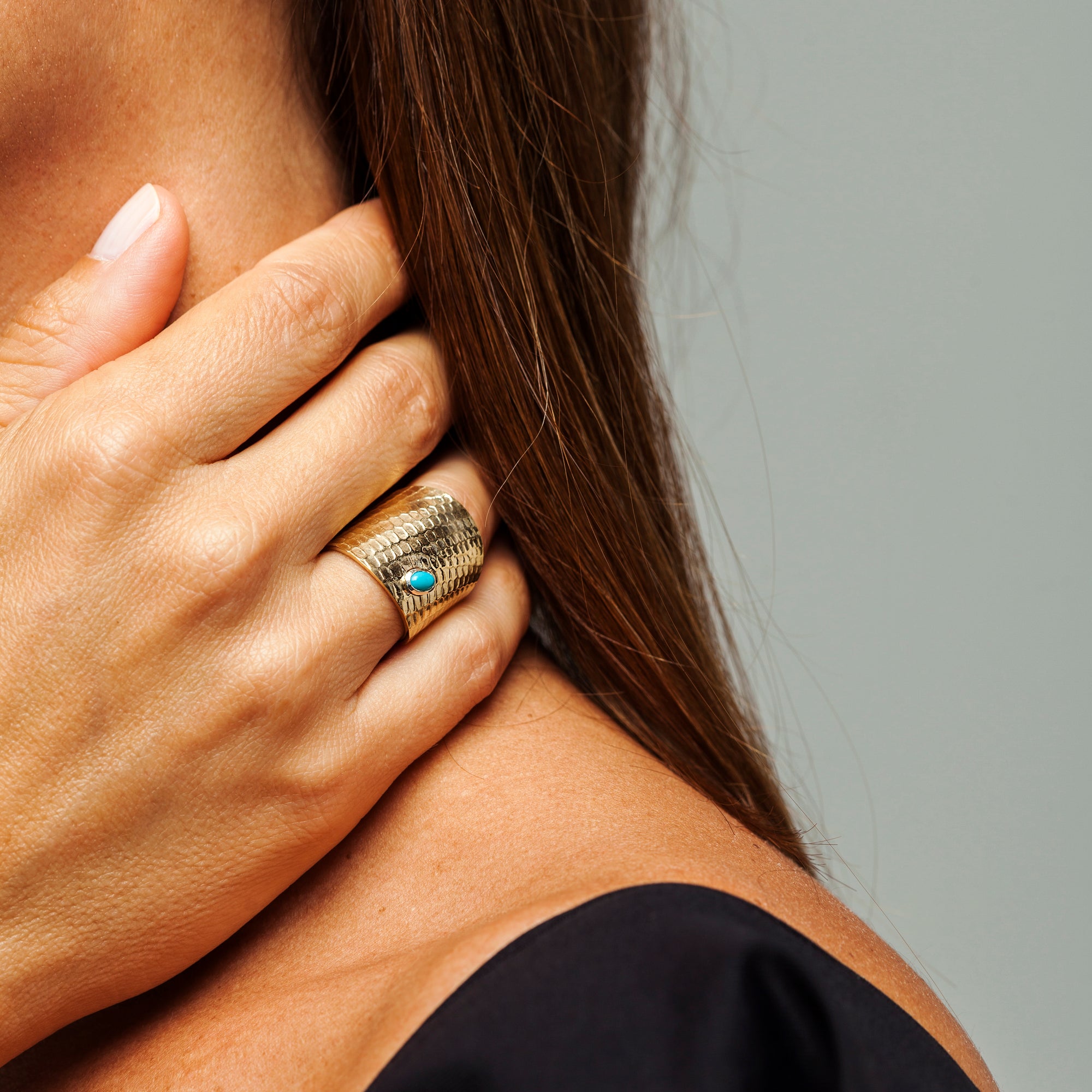 Close on-hand view of the Reptilia gold ring with natural gemstone.